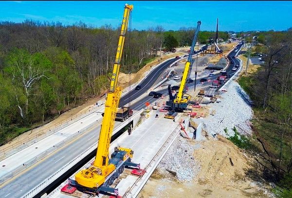 Construction site with large yellow cranes on a highway.