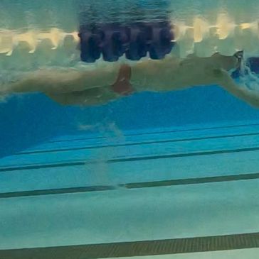 Underwater view of a swimmer in a pool executing a stroke.