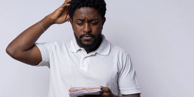 Man in white shirt looking confused while holding papers.