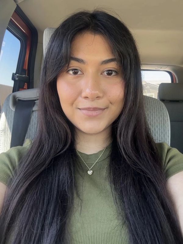 Young woman with long dark hair sitting in a car.