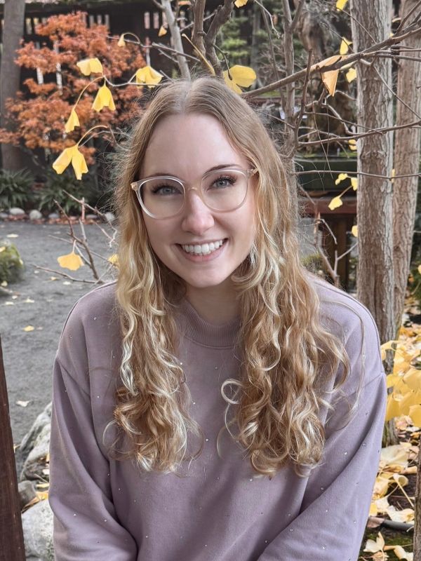 Smiling woman with glasses outdoors in autumn.
