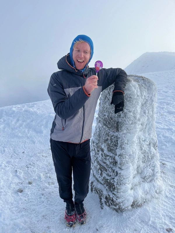 Rob Brown on his birthday with a lolly from his daughter standing on top of a snowy Helvellyn next t