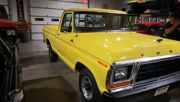 Yellow vintage Ford pickup truck in a garage.