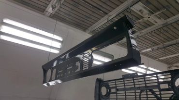Painted metal car grill parts hanging to dry in a workshop.