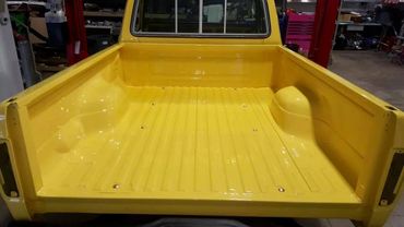 Bright yellow truck bed in a workshop setting.