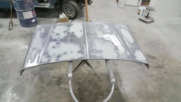 Car hood being prepped for painting in a workshop.