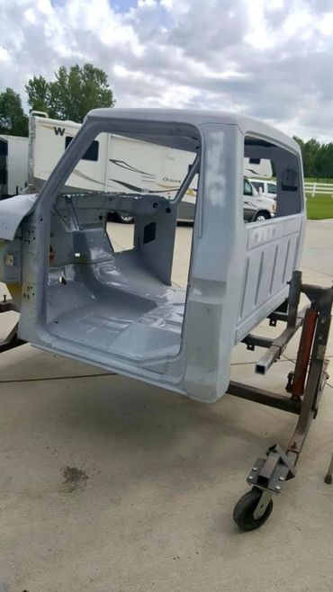 Bare truck cab shell mounted on a rotisserie stand for restoration.