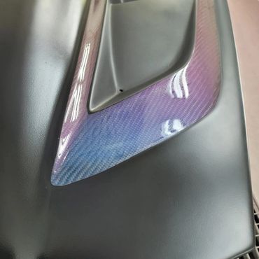 Close-up of a carbon fiber car interior panel with a glossy finish.