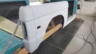 A car body undergoing restoration with parts removed and primer applied.