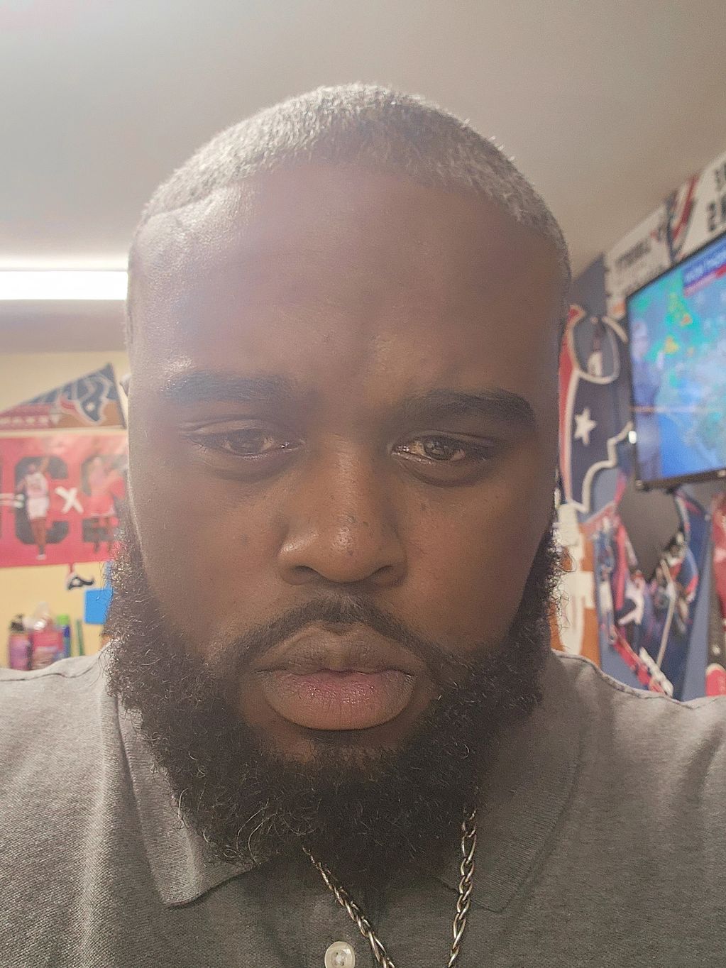 Close-up of a man with a beard in a room with sports decor.