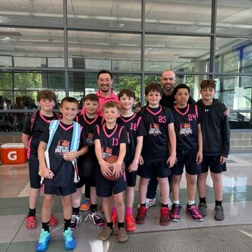 Young boys basketball team posing with their coaches indoors.