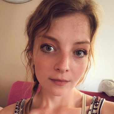 Close-up portrait of a young woman with braided hair and expressive eyes.