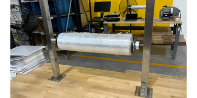 Industrial roll dispenser mounted on metal frame in a workshop.