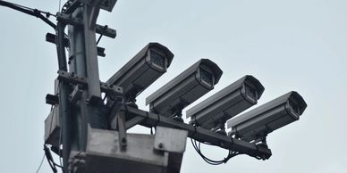 Four security cameras mounted on a pole against a clear sky.