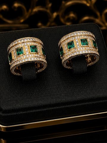 Luxurious gold rings with green gemstones and diamonds on a black velvet display.
