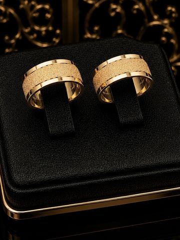 Elegant gold rings with textured center bands displayed on a black cushion.
