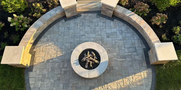 Circular stone fire pit with seating and garden surroundings.