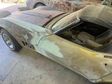 Classic car undergoing bodywork restoration in a garage.