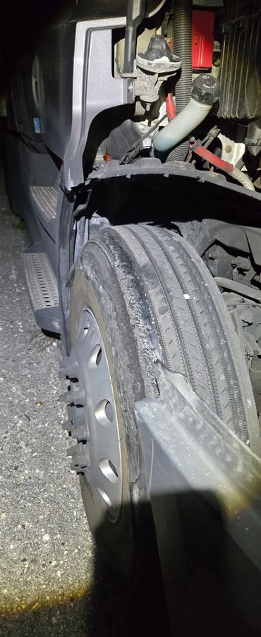 Severely damaged tire on a vehicle illuminated at night.
