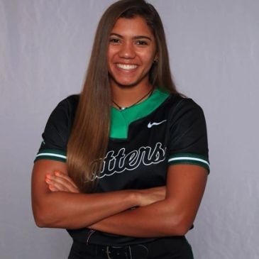Smiling athlete in black and green sports jersey with crossed arms.
