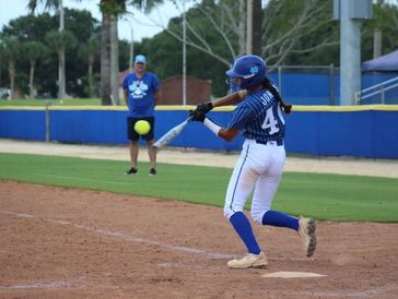 A softball player hits the ball during a game.