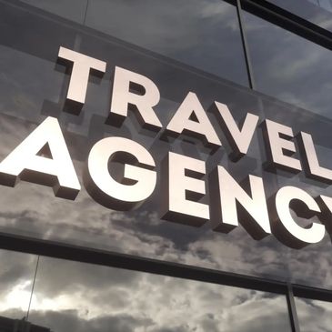 Modern travel agency sign on reflective glass building.