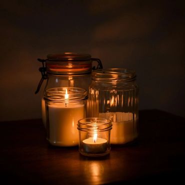 Four lit candles in glass jars creating a warm glow.