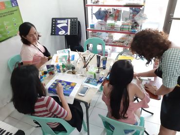 Four women engaged in a painting session around a table filled with art supplies.