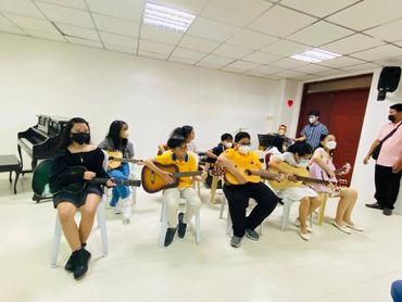 A group of children playing guitars in a classroom setting.