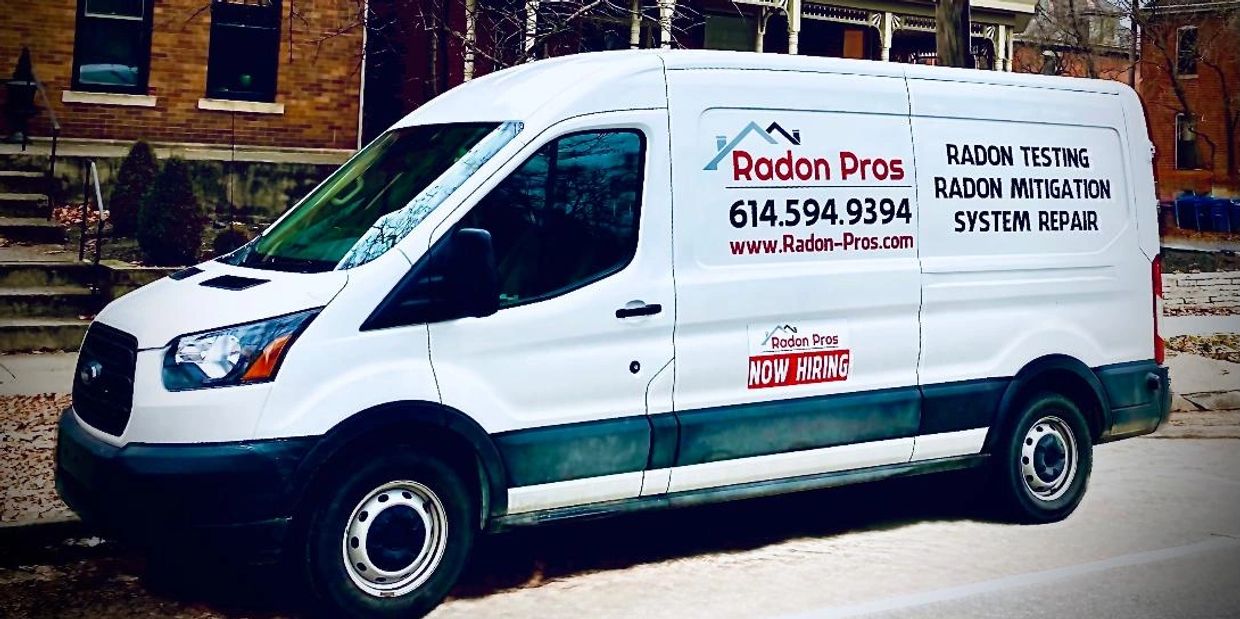 White Radon Pros service van parked on street.