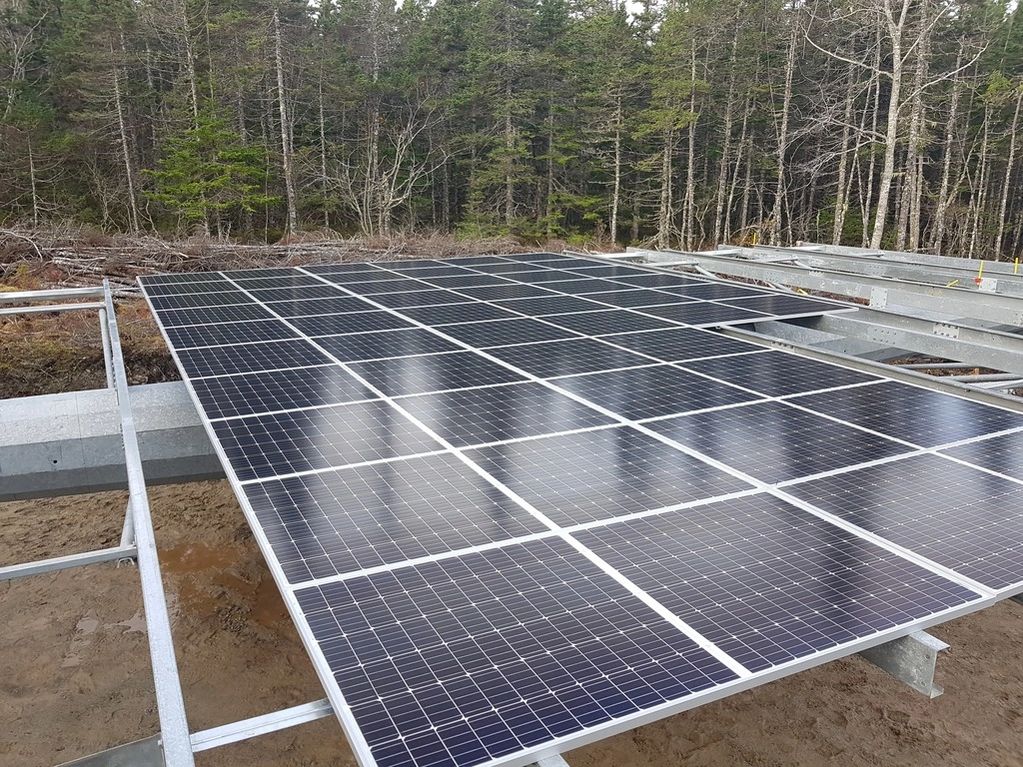 Some of the ninety solar panels to be mounted on tracker platform.  Panels and support beams are vis