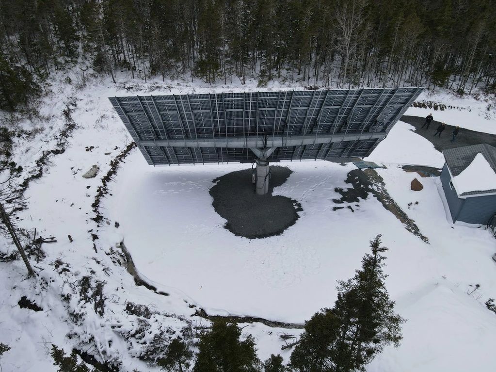 Rear of solar tracker with bifacial panels in winter snow.  Tracker is mounted on concrete pedestal.