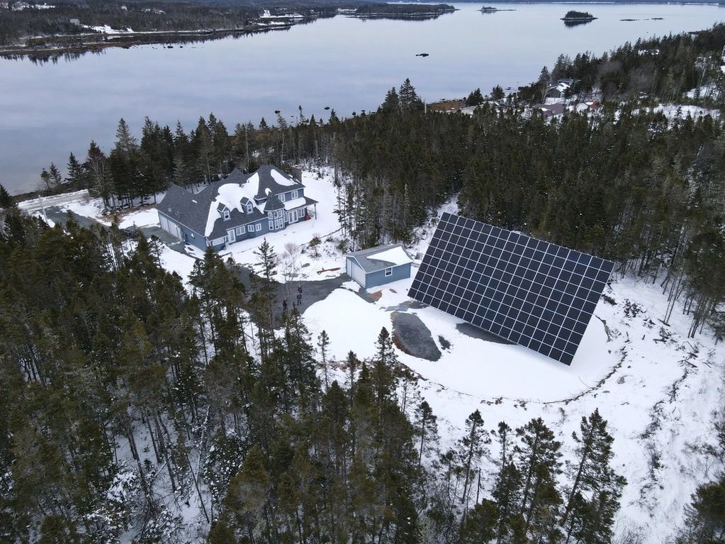 Two axis solar tracking array with 90 panels on an estate. In the background is a large home. Beyond