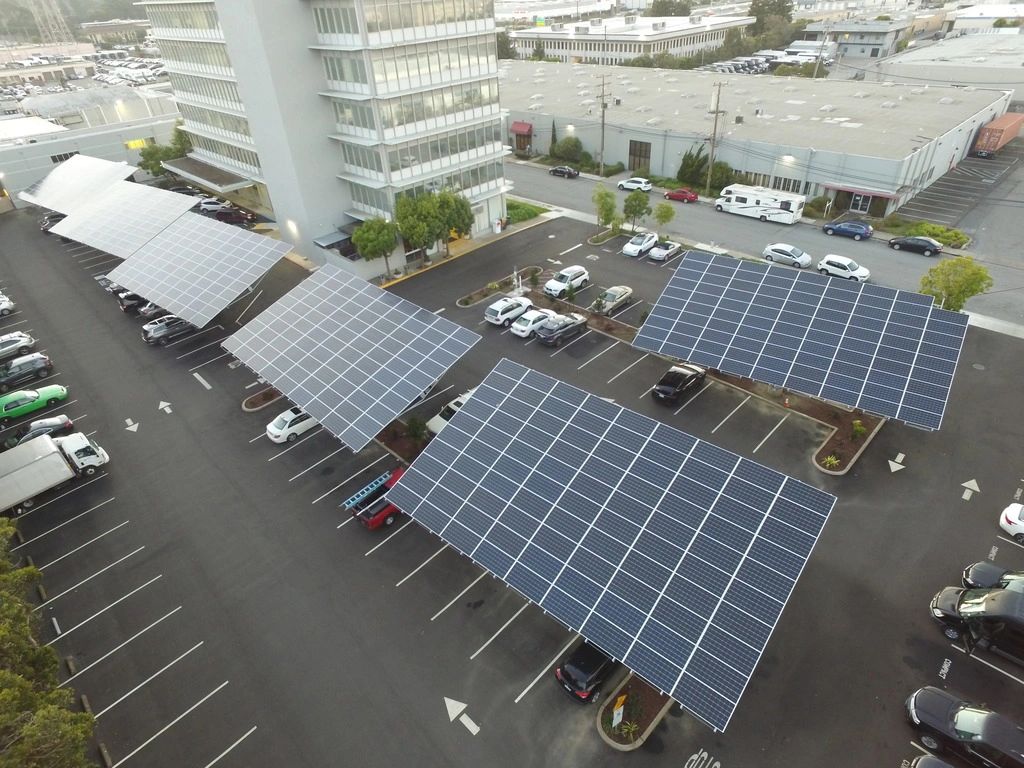 Six 2 axis solar trackers of 90 panels each, in an urban parking lot next to a high rise office buil