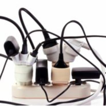 Overloaded power strip with multiple plugs and tangled cords.
