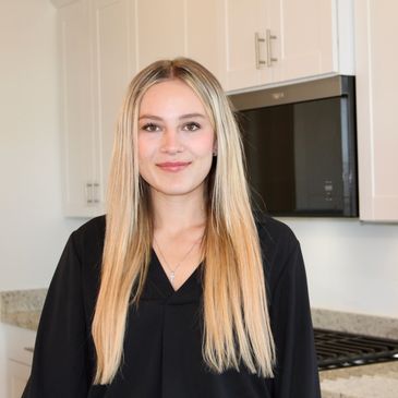 Smiling woman with long blonde hair in a modern kitchen.