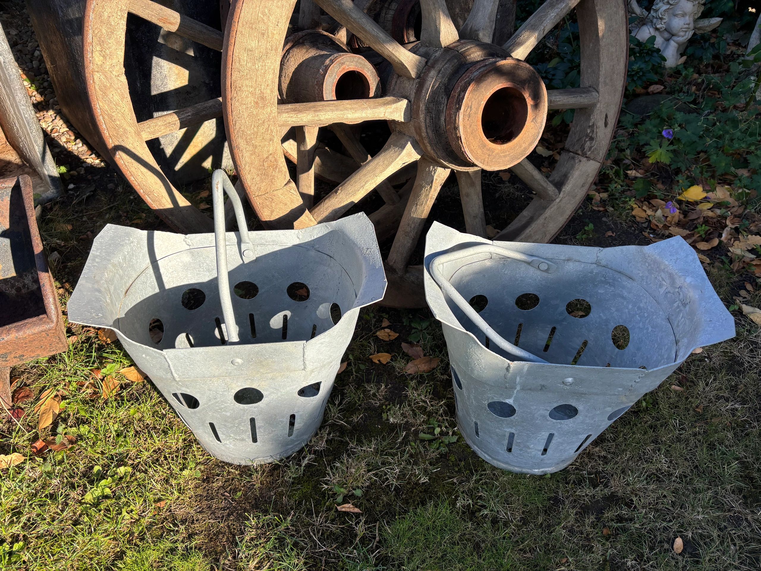 Two vintage metal coal scuttles and wooden wagon wheels.