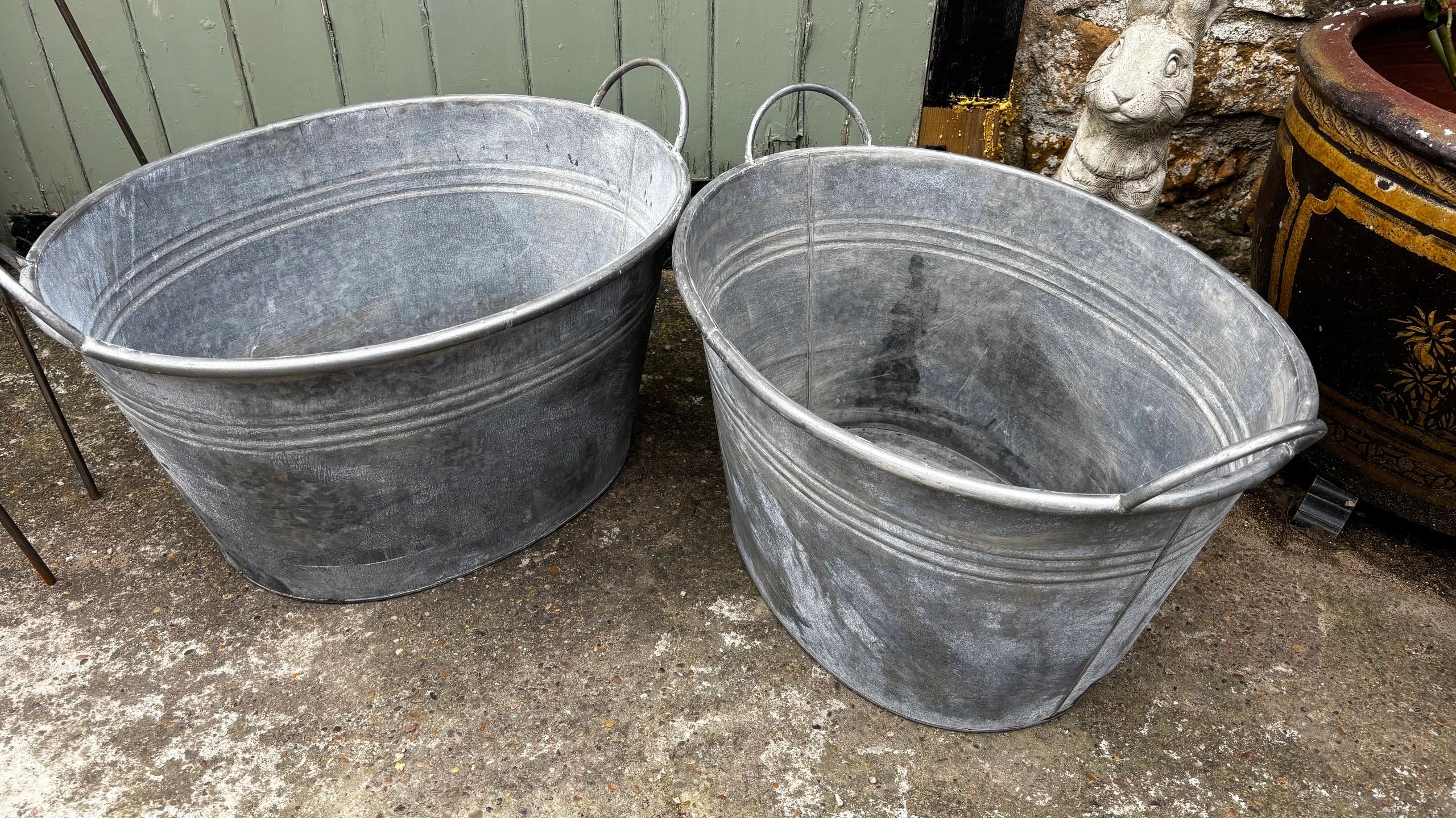 Two metal tubs placed outdoors on concrete ground.