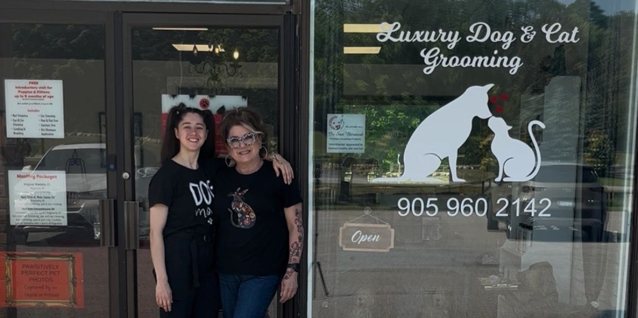 Two women standing happily outside a luxury dog and cat grooming shop.