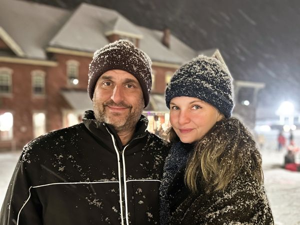 Couple bundled up in snow-covered winter clothing outdoors at night.