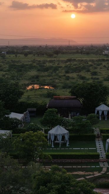 Sunset over a lush green landscape with garden tents.