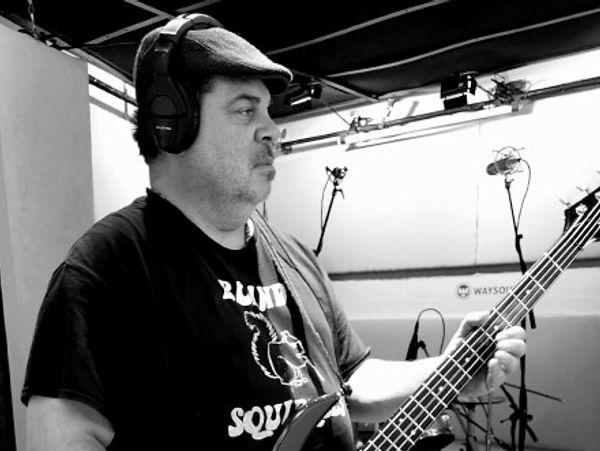 Man wearing headphones playing electric bass guitar in a studio.