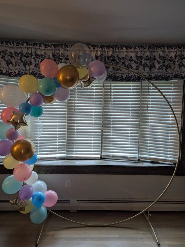 Metal circular balloon frame with colorful balloons attached.