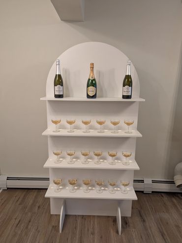 White stand with champagne bottles and glasses.