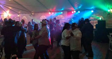 Couples dancing under colorful lights at an indoor party.