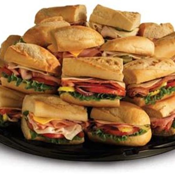 A platter filled with assorted sandwiches including ham, lettuce, and cheese.