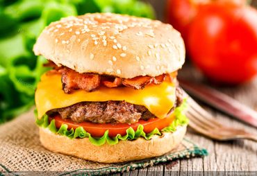 Classic bacon cheeseburger with lettuce and tomato on a sesame bun.