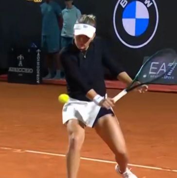 Tennis player hitting a backhand shot on a clay court.