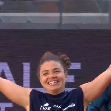 Smiling athlete raising arms in celebration on the field.