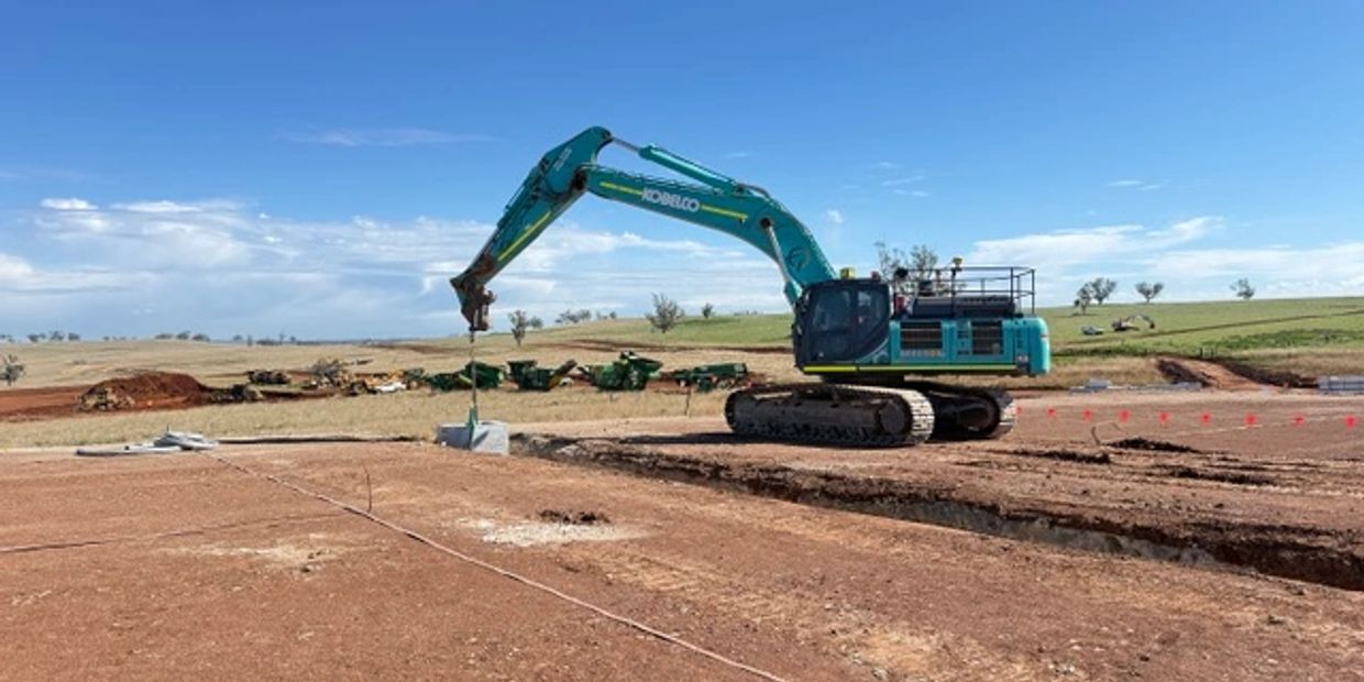 Large excavator working on a construction site in a rural area.